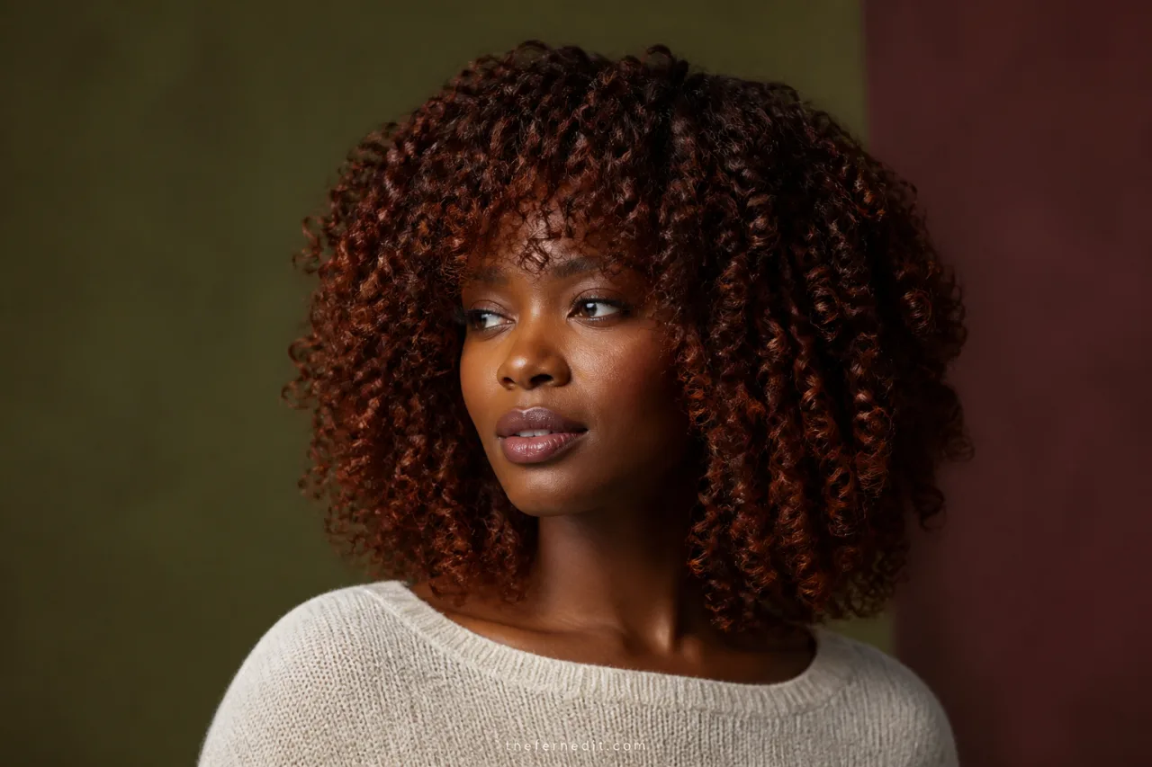 Voluminous shoulder-length curls in a rich auburn hair color with visible red-brown dimension from roots to ends.
